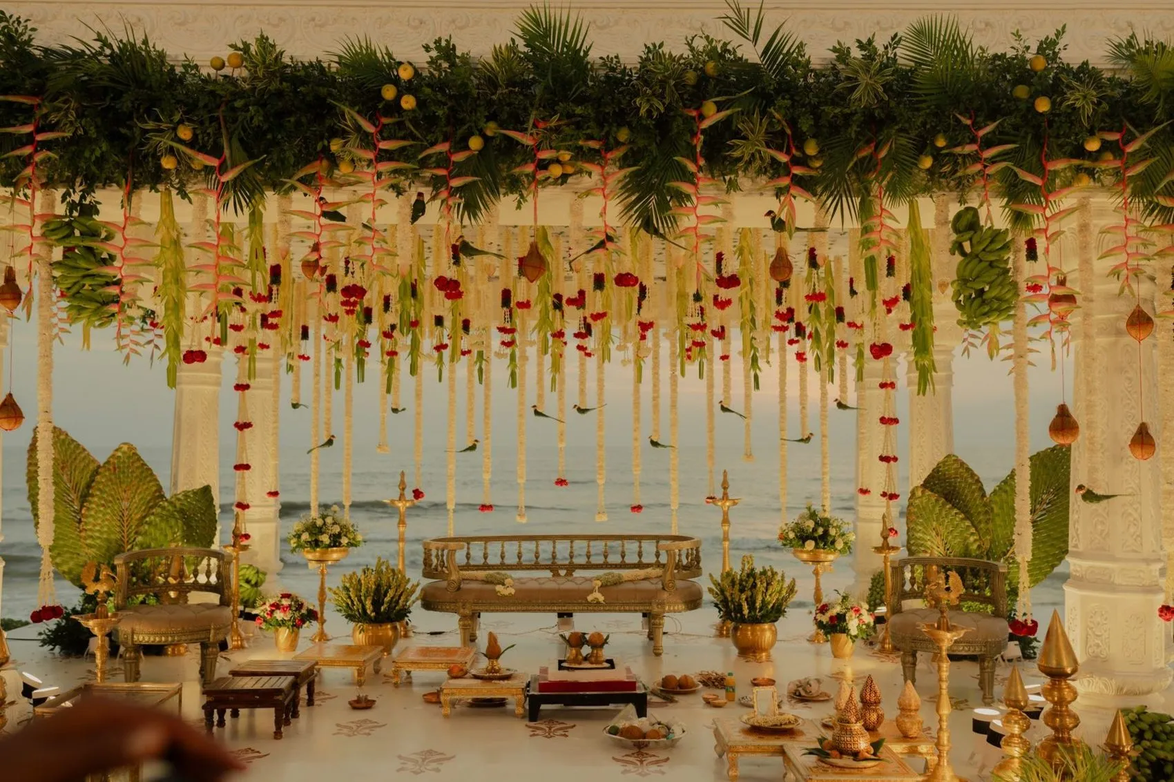 Floral wedding mandap set up by the water at sunset