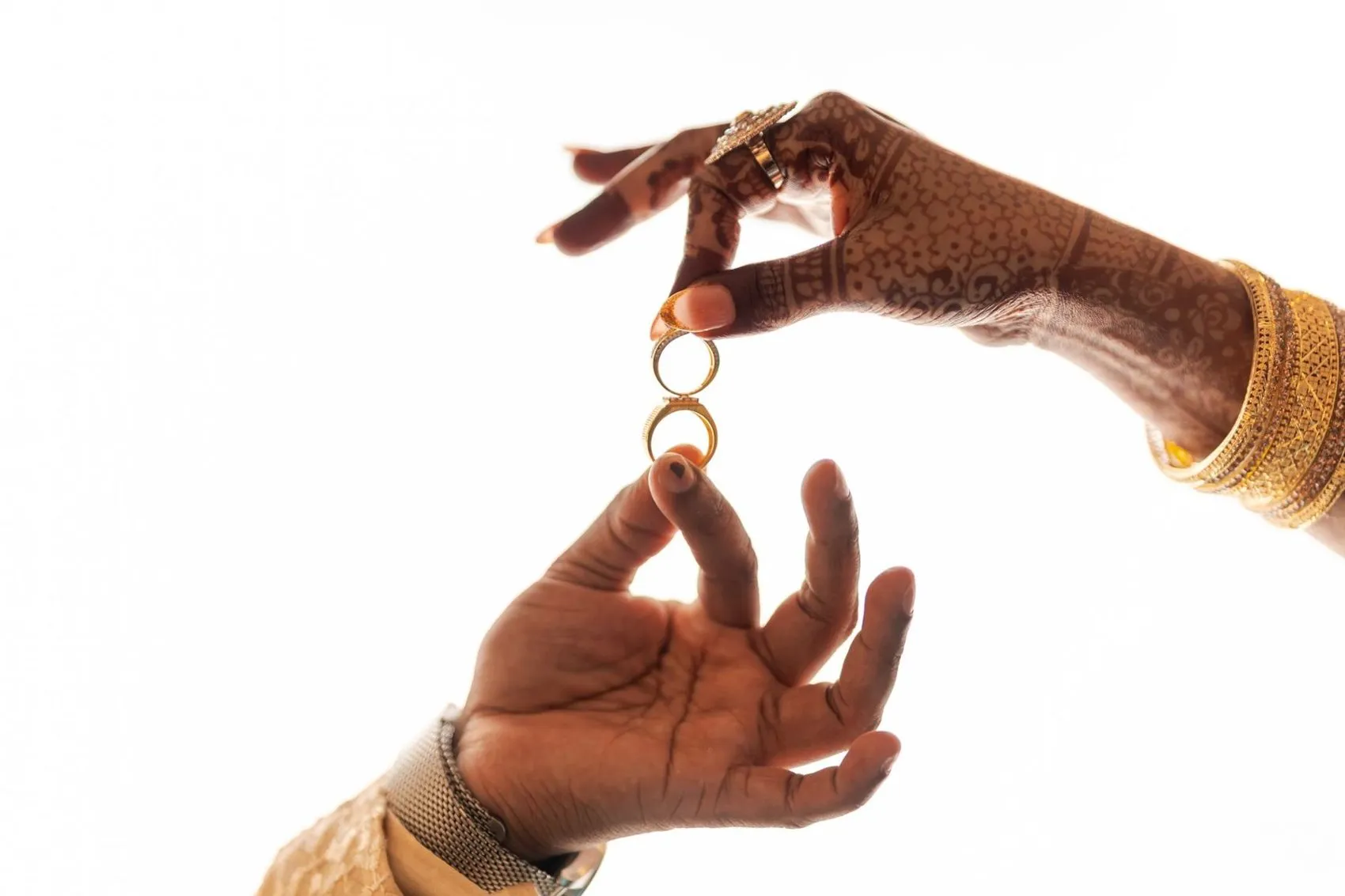 Hands with mehendi holding wedding rings